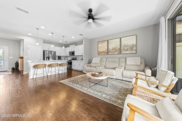 living room with ceiling fan and dark wood-type flooring