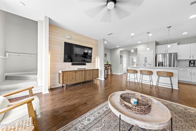 living room with dark hardwood / wood-style flooring, ceiling fan, and sink