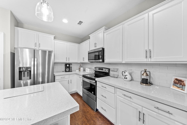 kitchen with dark wood-type flooring, white cabinets, hanging light fixtures, appliances with stainless steel finishes, and light stone counters