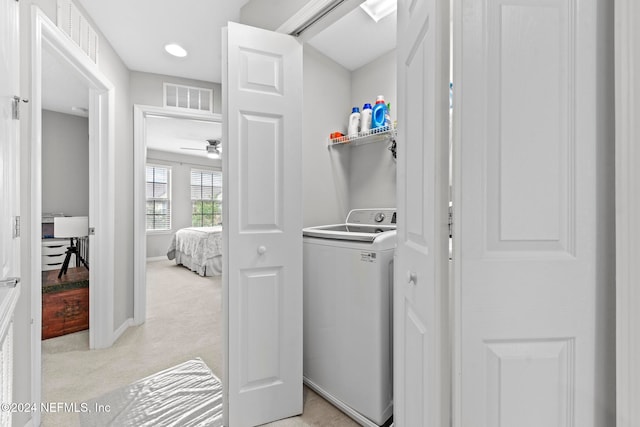 clothes washing area featuring light carpet and washer / clothes dryer