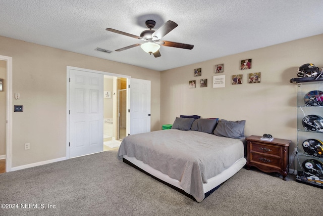 carpeted bedroom with a textured ceiling, ensuite bathroom, and ceiling fan