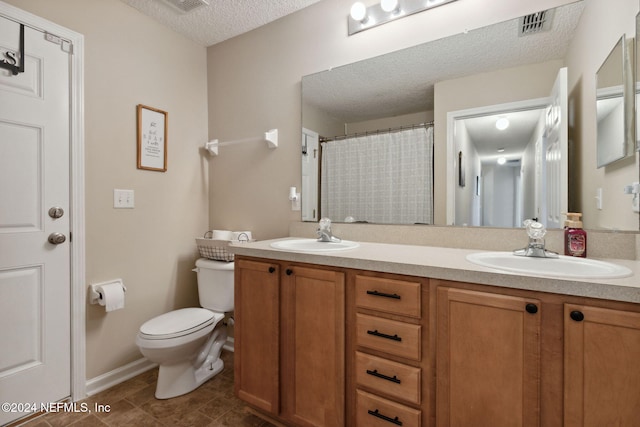 bathroom featuring tile patterned flooring, vanity, a textured ceiling, and toilet