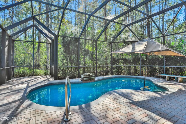 view of pool with glass enclosure and a patio