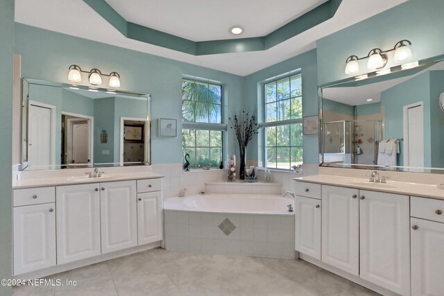 bathroom with tile patterned floors, vanity, independent shower and bath, and a tray ceiling