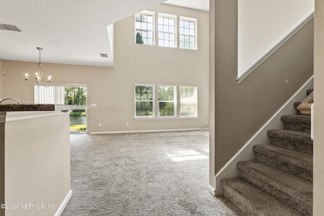 interior space featuring carpet flooring, plenty of natural light, a textured ceiling, and an inviting chandelier