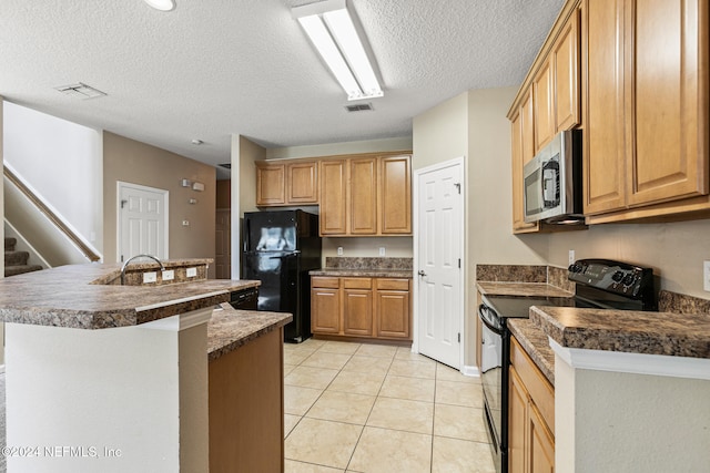 kitchen featuring black appliances, light tile patterned floors, an island with sink, and a textured ceiling