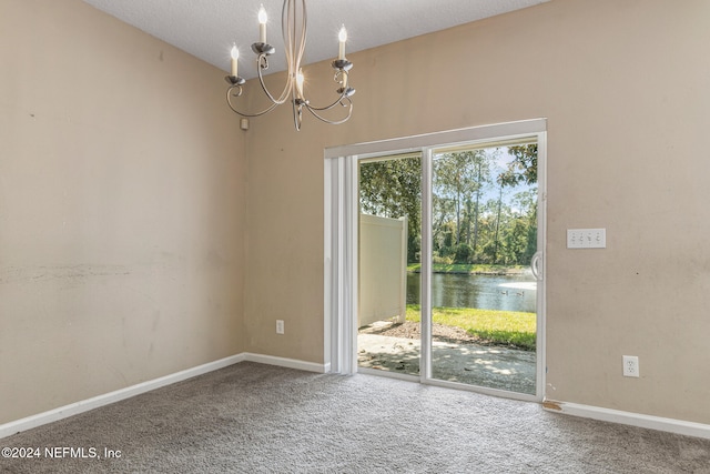 carpeted empty room featuring plenty of natural light, a water view, a chandelier, and a textured ceiling