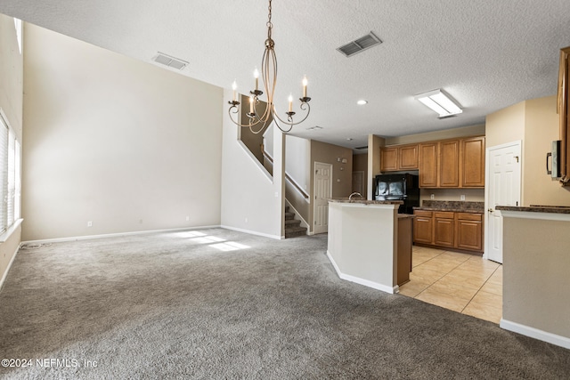 kitchen featuring pendant lighting, a kitchen island with sink, black refrigerator, a textured ceiling, and light colored carpet