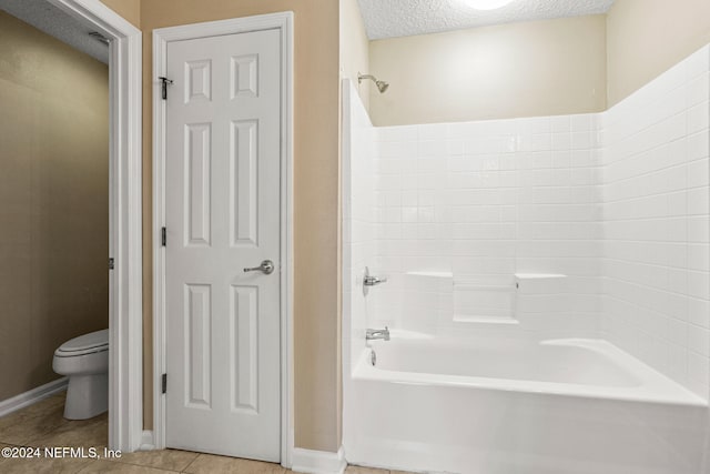 bathroom featuring tile patterned flooring, washtub / shower combination, a textured ceiling, and toilet