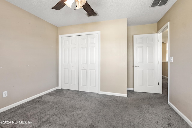 unfurnished bedroom with dark colored carpet, a textured ceiling, a closet, and ceiling fan