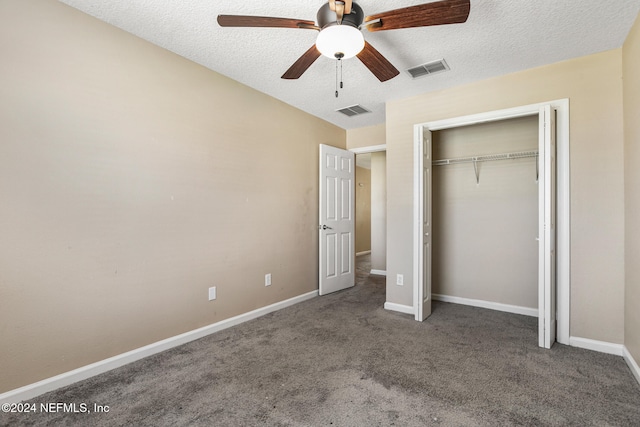 unfurnished bedroom with ceiling fan, a closet, a textured ceiling, and dark colored carpet