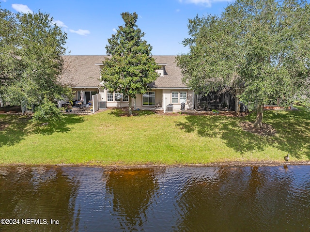 rear view of house with a yard and a water view