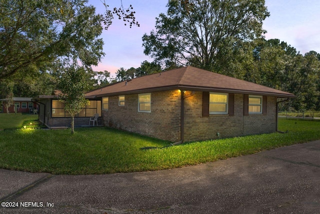 property exterior at dusk featuring a lawn