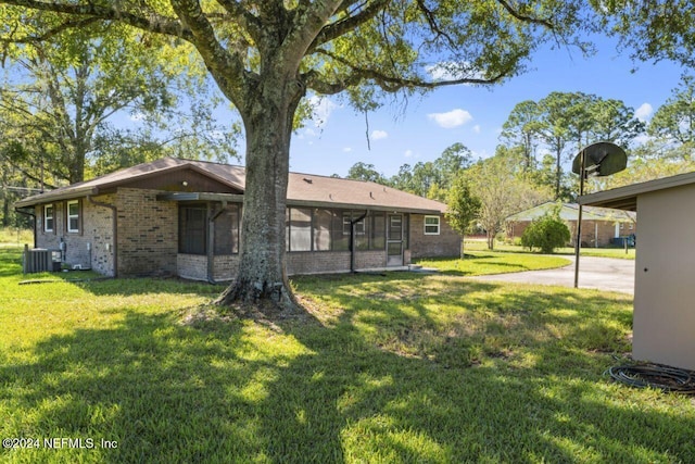 back of house with central AC unit, a sunroom, and a yard