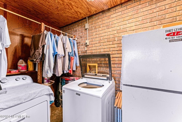 laundry room featuring washing machine and dryer, wooden ceiling, and brick wall