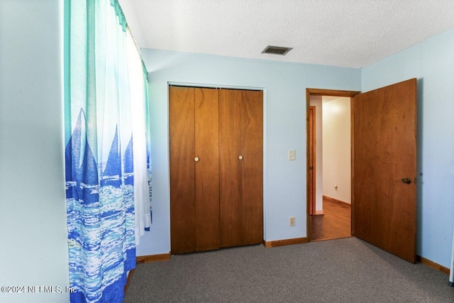 unfurnished bedroom featuring carpet flooring, a textured ceiling, and a closet