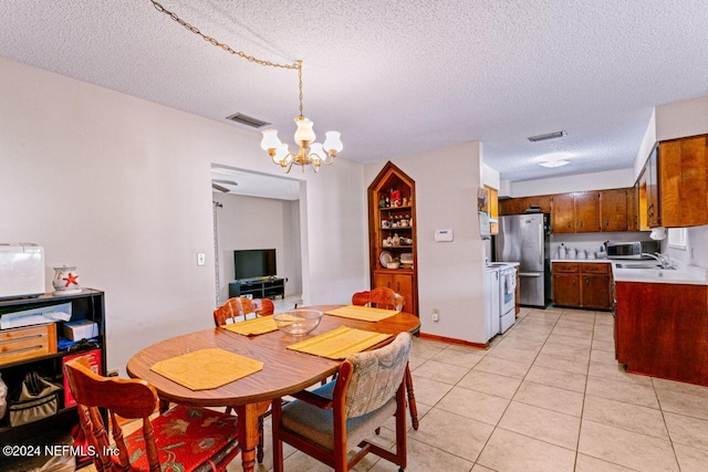 dining room with light tile patterned floors, a textured ceiling, and an inviting chandelier