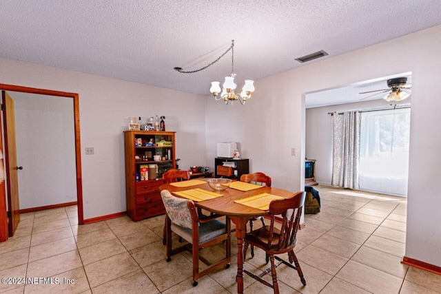 dining area with ceiling fan with notable chandelier, light tile patterned floors, and a textured ceiling