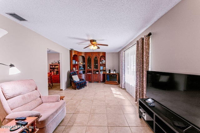 living room with ceiling fan, light tile patterned floors, and a textured ceiling