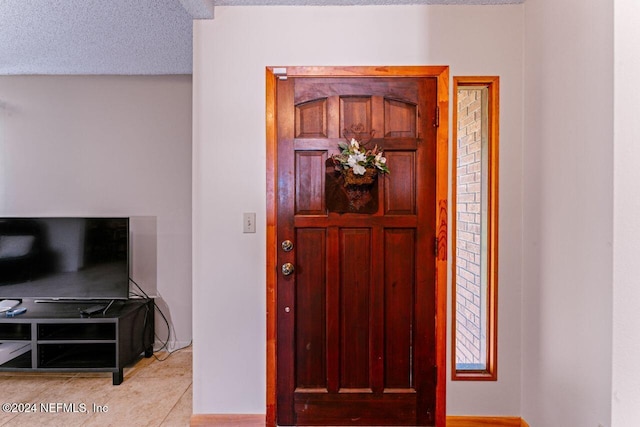 entryway featuring light tile patterned floors and a textured ceiling