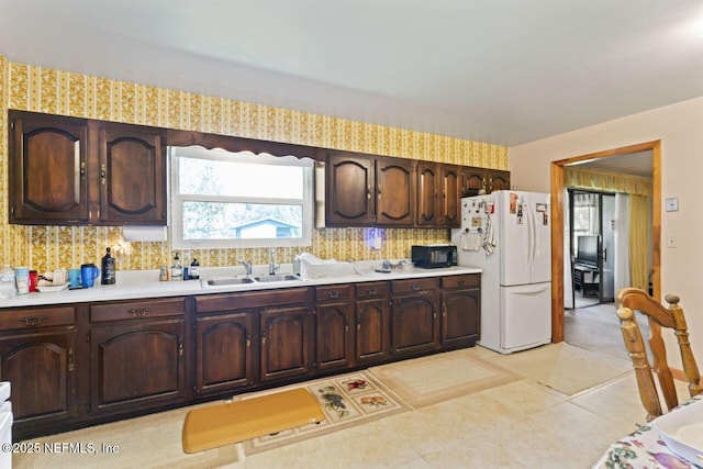 kitchen with sink, white fridge, and dark brown cabinetry