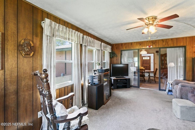 carpeted living room with a textured ceiling, wood walls, and ceiling fan