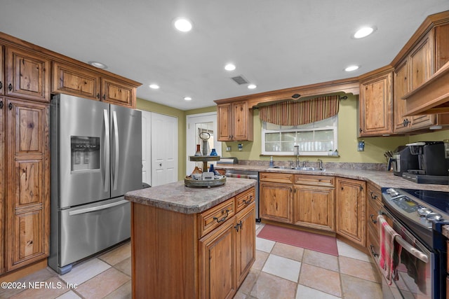 kitchen featuring a kitchen island, sink, stainless steel appliances, and light tile patterned flooring