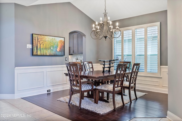 dining area with a healthy amount of sunlight, light hardwood / wood-style floors, an inviting chandelier, and lofted ceiling