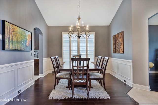 dining space with wood-type flooring, lofted ceiling, and a notable chandelier