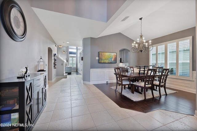 tiled dining room with vaulted ceiling, an inviting chandelier, and plenty of natural light