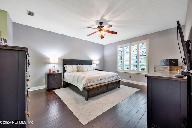 bedroom featuring ceiling fan, dark hardwood / wood-style flooring, and a textured ceiling