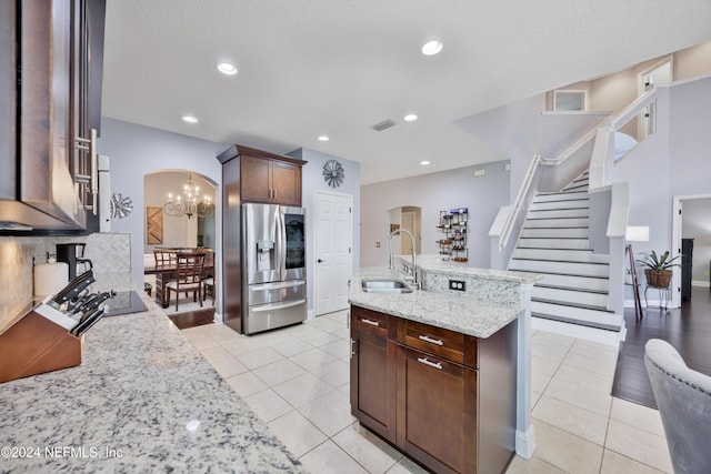 kitchen featuring stainless steel fridge, light stone countertops, light tile patterned floors, and sink