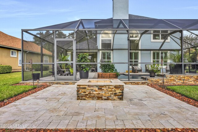 rear view of property with glass enclosure and a patio area