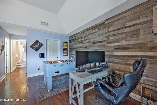 office with a textured ceiling, dark wood-type flooring, wooden walls, and vaulted ceiling