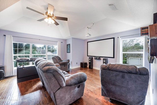 home theater with hardwood / wood-style flooring, a raised ceiling, and ceiling fan