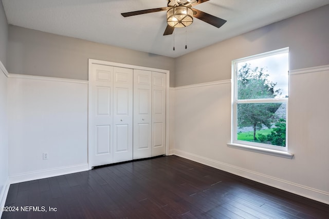 unfurnished bedroom featuring ceiling fan, a closet, and dark wood-type flooring