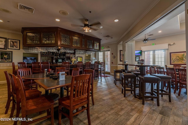 dining room featuring ceiling fan, ornamental molding, and bar area