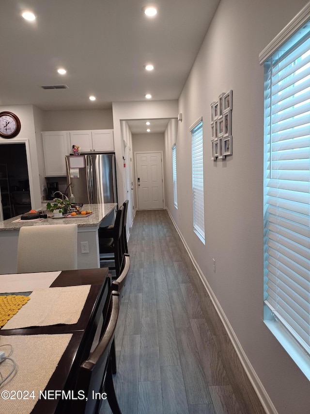 kitchen featuring stainless steel fridge, light stone counters, white cabinetry, and dark wood-type flooring