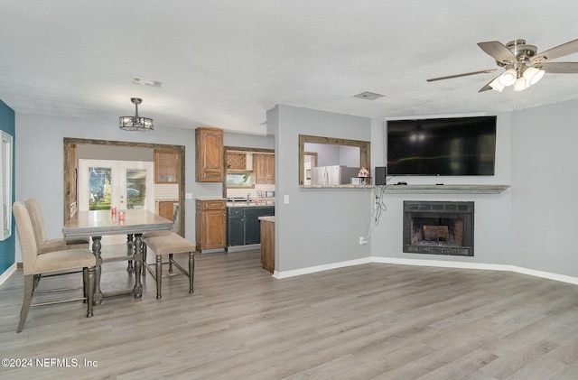 interior space featuring ceiling fan, light hardwood / wood-style floors, a textured ceiling, and french doors