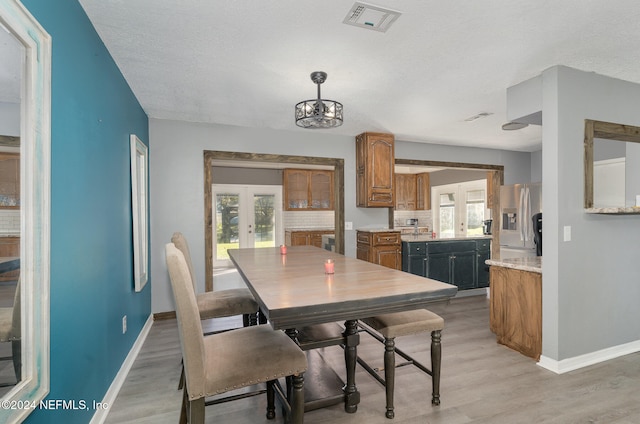 dining room with french doors, a textured ceiling, and light wood-type flooring