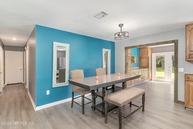 dining area with a chandelier, a textured ceiling, and light hardwood / wood-style floors