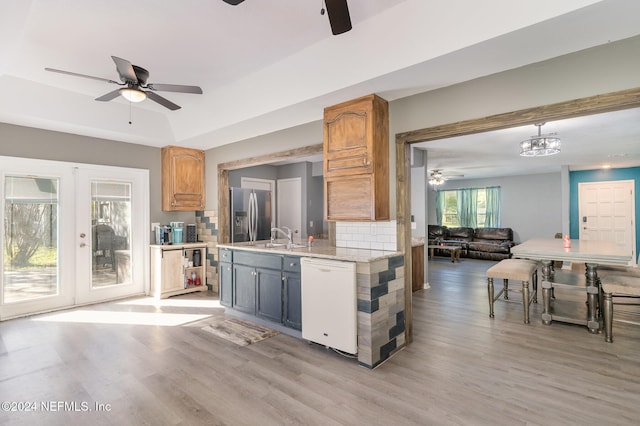 kitchen featuring decorative backsplash, light wood-type flooring, pendant lighting, dishwasher, and stainless steel fridge with ice dispenser