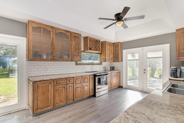 kitchen featuring french doors, stainless steel appliances, a raised ceiling, light hardwood / wood-style floors, and decorative backsplash