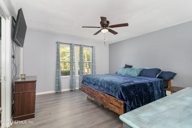 bedroom with ceiling fan, a textured ceiling, and hardwood / wood-style flooring