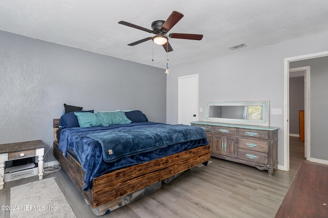 bedroom featuring ceiling fan, a textured ceiling, and light hardwood / wood-style flooring