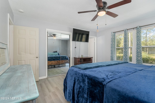 bedroom with ceiling fan, light hardwood / wood-style floors, a textured ceiling, and a closet