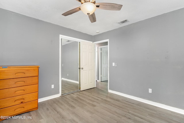 unfurnished bedroom with ceiling fan, light wood-type flooring, and a closet