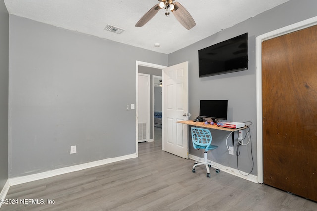 unfurnished office with ceiling fan, light hardwood / wood-style floors, and a textured ceiling