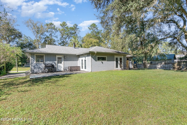 back of property with a lawn, a patio area, and french doors