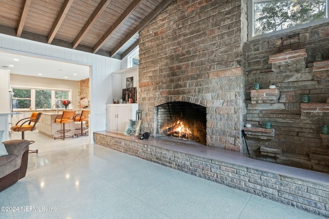 unfurnished living room with beam ceiling, a large fireplace, high vaulted ceiling, and wood ceiling